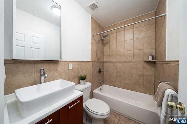 bathroom with toilet, visible vents, vanity, tile walls, and  shower combination