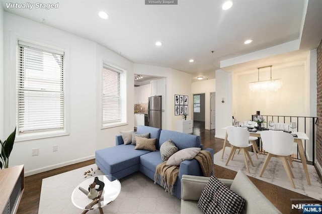 living room featuring a notable chandelier, dark wood-type flooring, baseboards, and recessed lighting