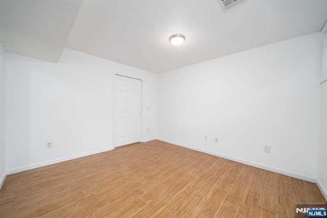 empty room featuring light wood-style floors, visible vents, and baseboards