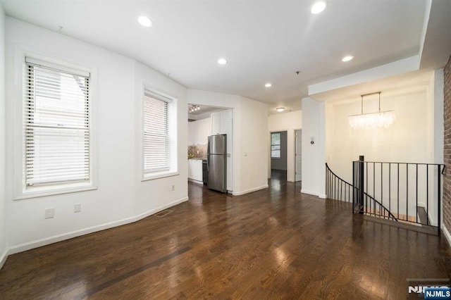 unfurnished room with a notable chandelier, dark wood-type flooring, baseboards, and recessed lighting