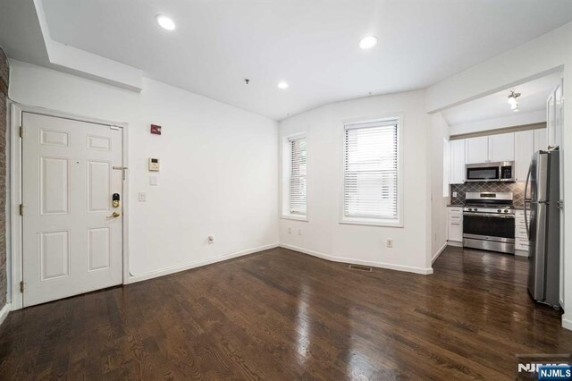 unfurnished living room with baseboards, dark wood-type flooring, and recessed lighting