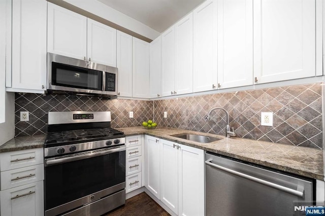 kitchen featuring stainless steel appliances, decorative backsplash, a sink, and white cabinets