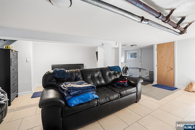 living area with washer / dryer, light tile patterned floors, and baseboards