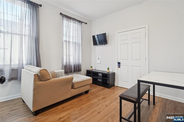 living area with light wood finished floors, radiator heating unit, and baseboards