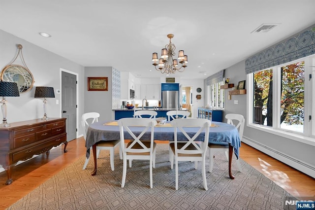 dining room featuring a notable chandelier, a baseboard radiator, recessed lighting, visible vents, and light wood-style floors