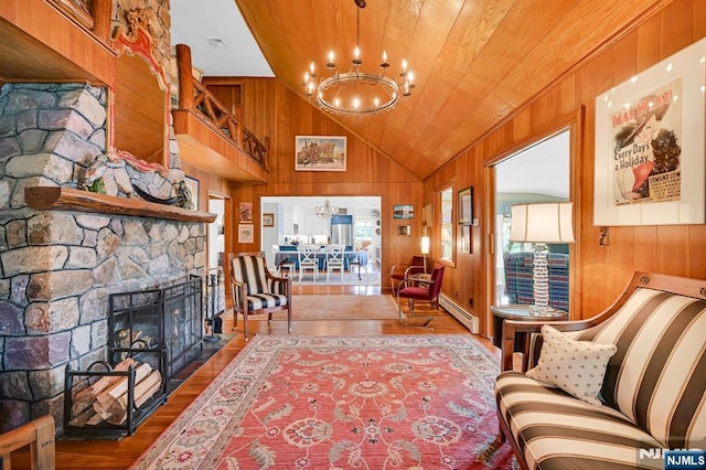 living room with wooden walls, a baseboard radiator, wood finished floors, a fireplace, and a chandelier