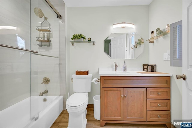 full bath with shower / bath combination with glass door, vanity, toilet, and wood finished floors