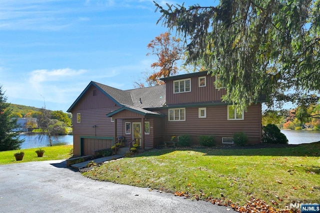 view of front of house featuring a garage, a front yard, and a water view