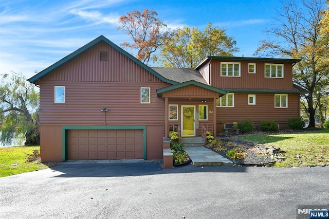 view of front facade with aphalt driveway, roof with shingles, and an attached garage