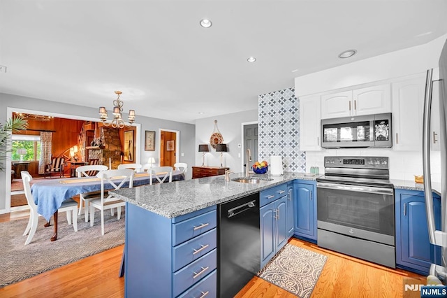 kitchen featuring blue cabinets, stainless steel appliances, a peninsula, a sink, and light wood-style floors