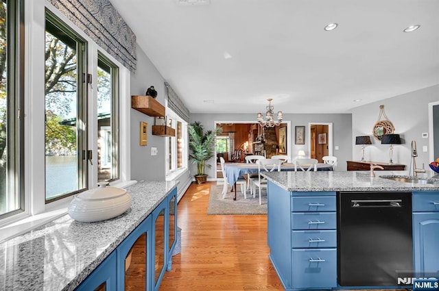 kitchen featuring dishwasher, light wood-style flooring, an inviting chandelier, blue cabinetry, and a sink