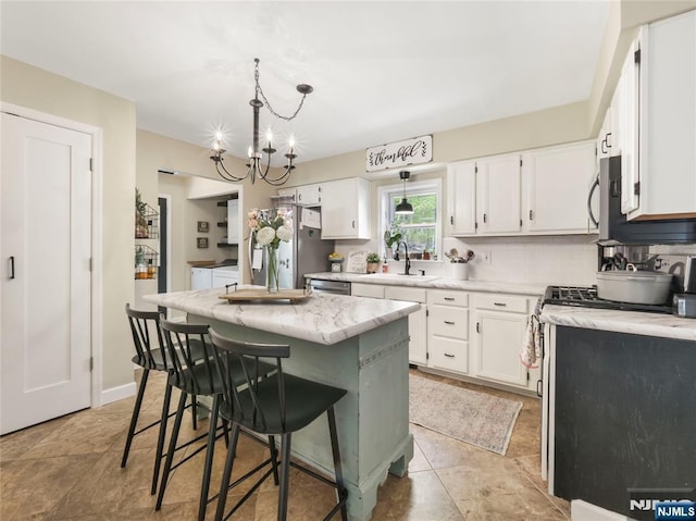 kitchen featuring hanging light fixtures, a kitchen island, white cabinets, and a sink