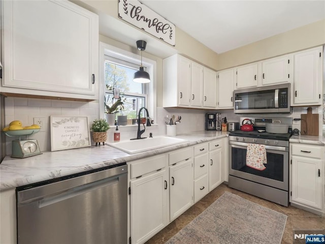 kitchen with stainless steel appliances, a sink, decorative light fixtures, and white cabinets