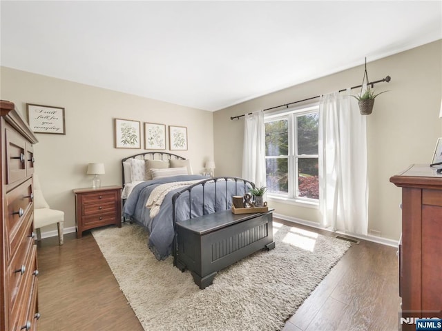 bedroom with dark wood-style floors, baseboards, and visible vents