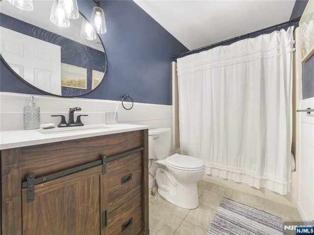 full bathroom featuring tile patterned flooring, toilet, a wainscoted wall, shower / tub combo, and vanity