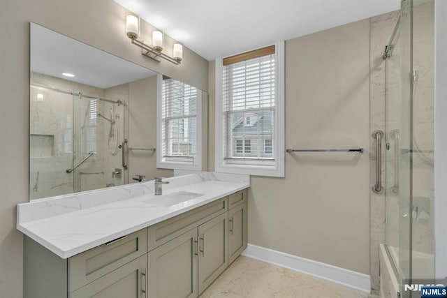 bathroom with marble finish floor, vanity, baseboards, and an enclosed shower