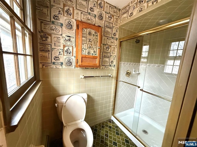 full bath featuring wainscoting, toilet, and tile walls