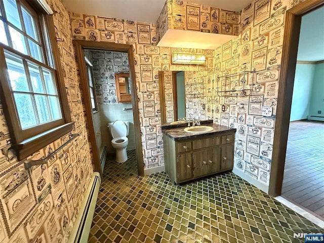 bathroom featuring a baseboard radiator, toilet, vanity, a healthy amount of sunlight, and wallpapered walls