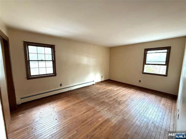 spare room with a baseboard radiator, baseboards, and hardwood / wood-style floors