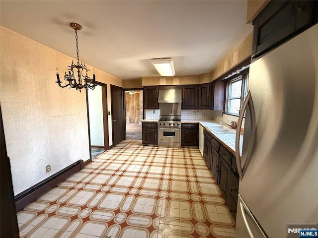 kitchen featuring wall chimney exhaust hood, appliances with stainless steel finishes, light countertops, and dark brown cabinets