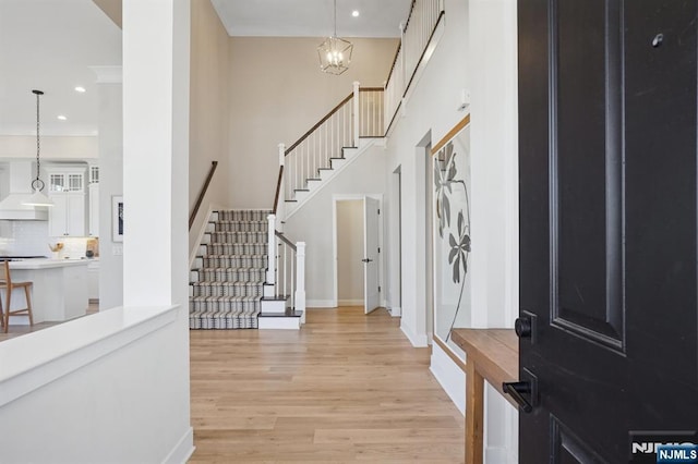 entryway featuring recessed lighting, light wood-style flooring, a high ceiling, baseboards, and stairs