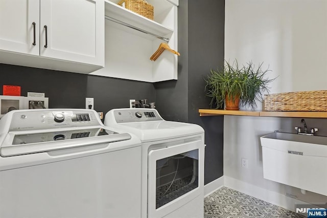 clothes washing area with baseboards, cabinet space, a sink, and washing machine and clothes dryer