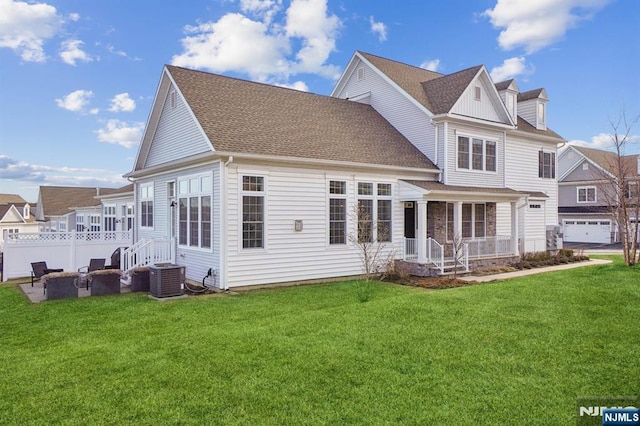 back of property with a shingled roof, central AC unit, and a lawn