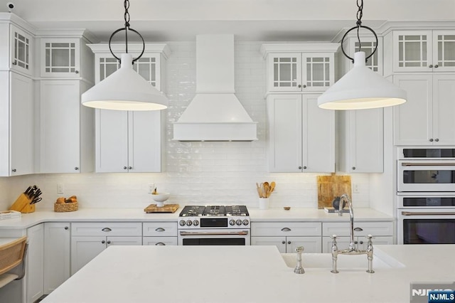 kitchen featuring white appliances, white cabinets, light countertops, custom exhaust hood, and tasteful backsplash