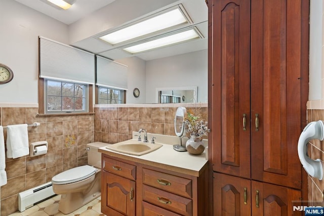 bathroom featuring a baseboard radiator, toilet, vanity, tile walls, and a closet