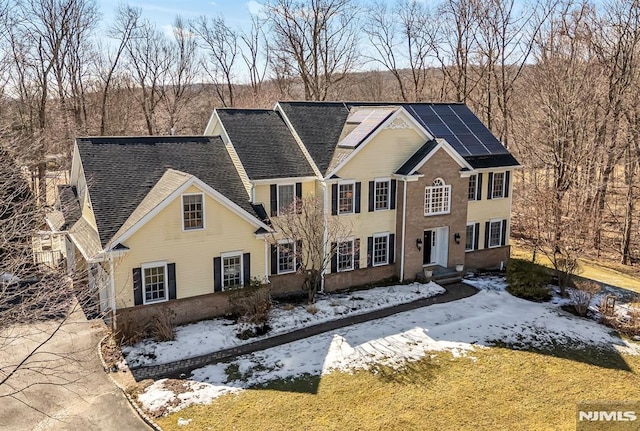 colonial-style house with solar panels and roof with shingles