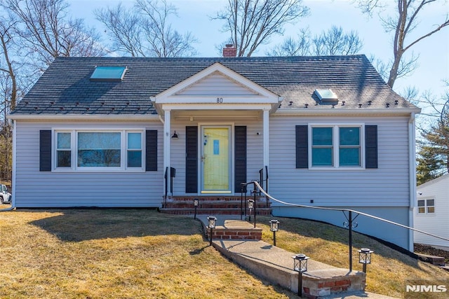 view of front of home with entry steps, a chimney, and a front yard