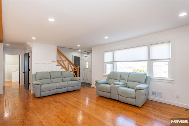 living area featuring recessed lighting, visible vents, baseboards, stairs, and light wood-style floors