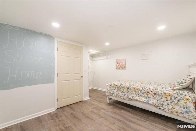 bedroom with baseboards, wood finished floors, and recessed lighting