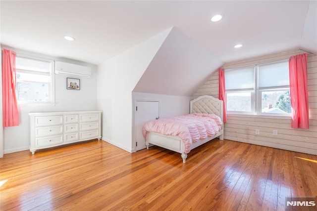 bedroom with recessed lighting, hardwood / wood-style floors, an AC wall unit, vaulted ceiling, and baseboards