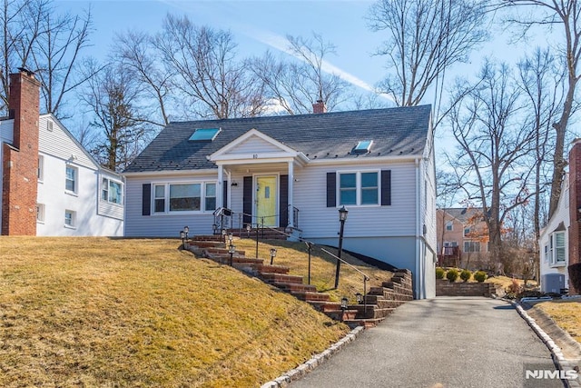 bungalow featuring a front yard, cooling unit, driveway, and a chimney