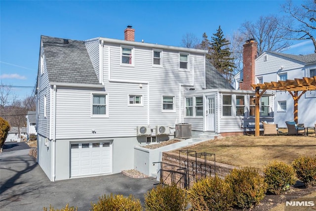 back of house with a chimney, an attached garage, central AC unit, fence, and a pergola