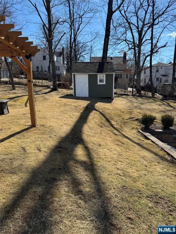 view of yard featuring an outdoor structure, driveway, a residential view, a pergola, and a shed