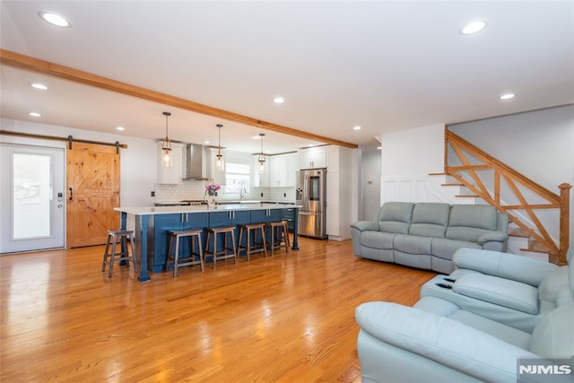 living area featuring a barn door, light wood-style flooring, beamed ceiling, stairs, and recessed lighting