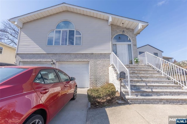 view of front facade featuring driveway, brick siding, and an attached garage