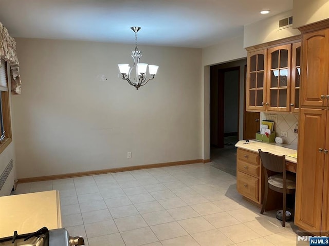 kitchen with visible vents, light countertops, backsplash, brown cabinets, and glass insert cabinets