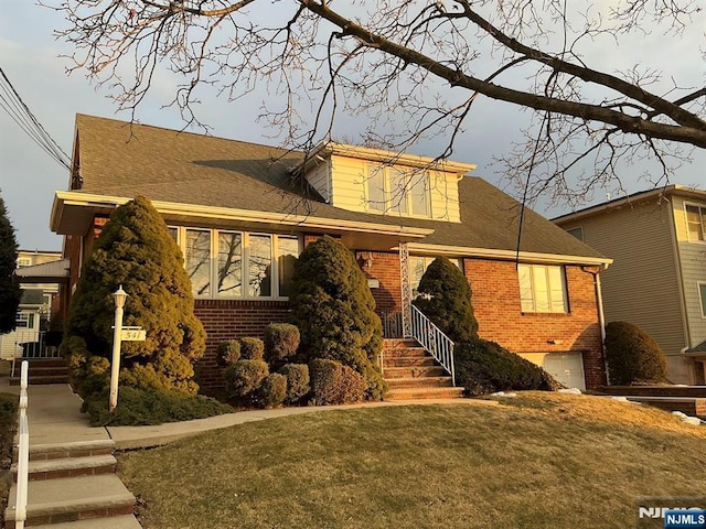 view of front of property featuring an attached garage, a shingled roof, and brick siding