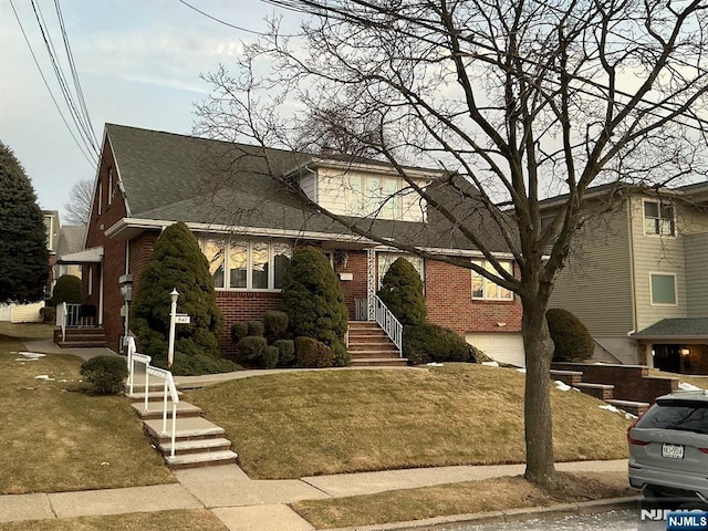 view of front of property featuring a shingled roof, a front lawn, and brick siding