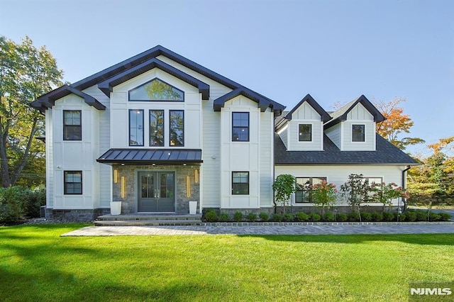 modern inspired farmhouse featuring a front yard, a standing seam roof, french doors, board and batten siding, and metal roof