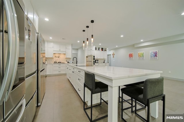 kitchen featuring recessed lighting, stainless steel fridge, white cabinets, and light stone countertops