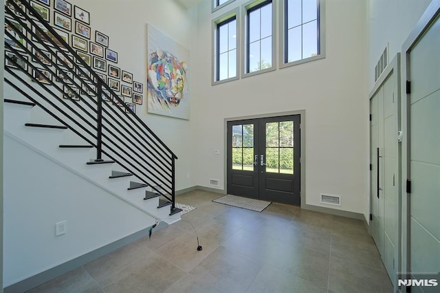 foyer with visible vents, french doors, stairway, and a towering ceiling