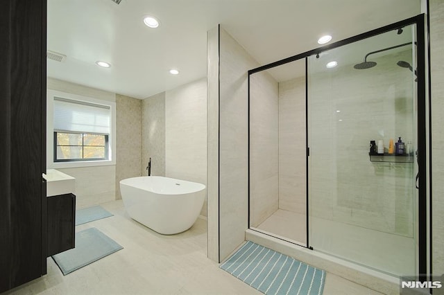 full bathroom with visible vents, a freestanding tub, recessed lighting, a stall shower, and tile walls