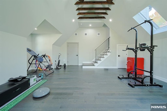 workout room with visible vents, high vaulted ceiling, wood finished floors, a skylight, and baseboards