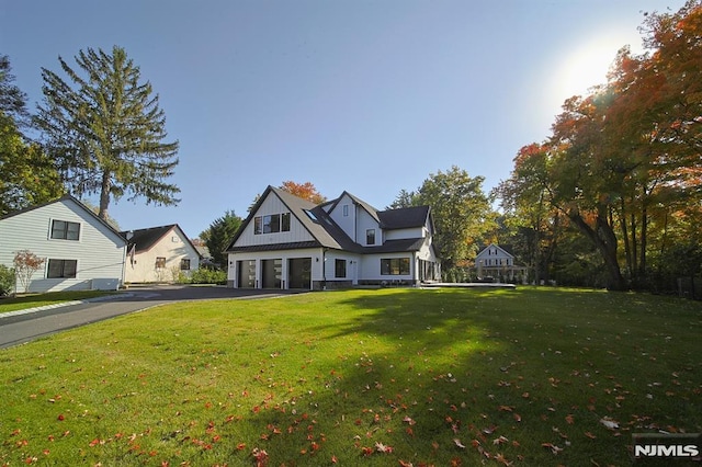 view of front of home featuring aphalt driveway, an attached garage, board and batten siding, and a front yard