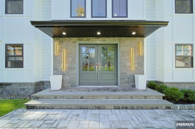 property entrance featuring stone siding, covered porch, and french doors