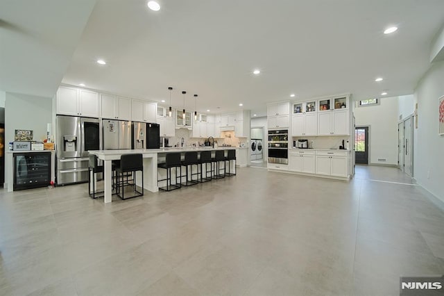 interior space with beverage cooler, appliances with stainless steel finishes, white cabinets, and light countertops